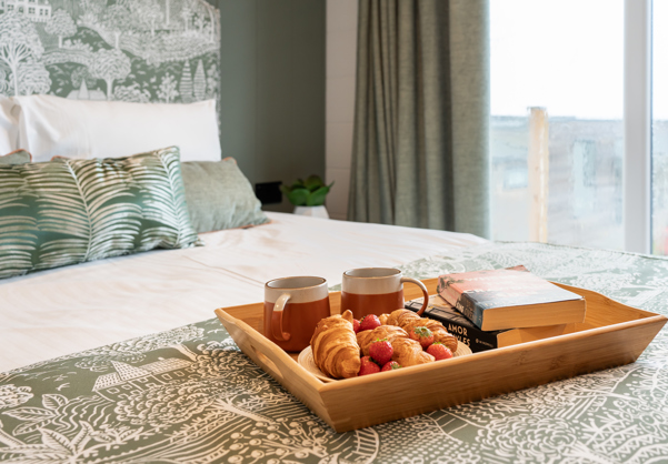 Bedroom focussing on comfy bed serenely decorated with breakfast-in-bed tray