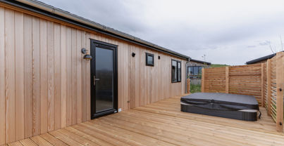 External of a luxury lodge on pitch with decking and hot tub