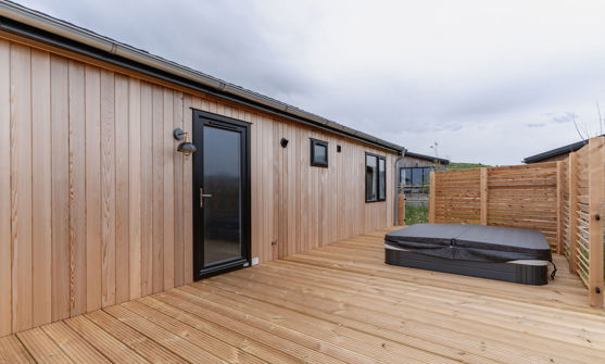 External of a luxury lodge on pitch with decking and hot tub