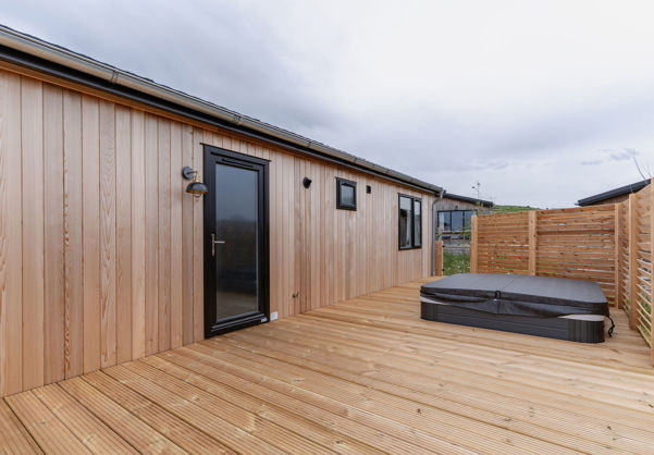 External of a luxury lodge on pitch with decking and hot tub