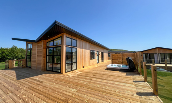 External of a luxury lodge on pitch with decking and hot tub