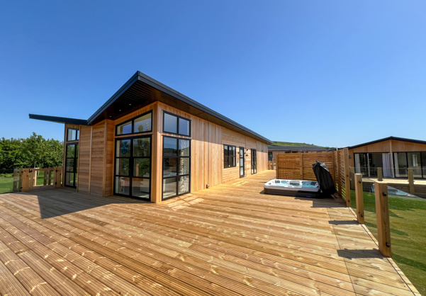 External of a luxury lodge on pitch with decking and hot tub