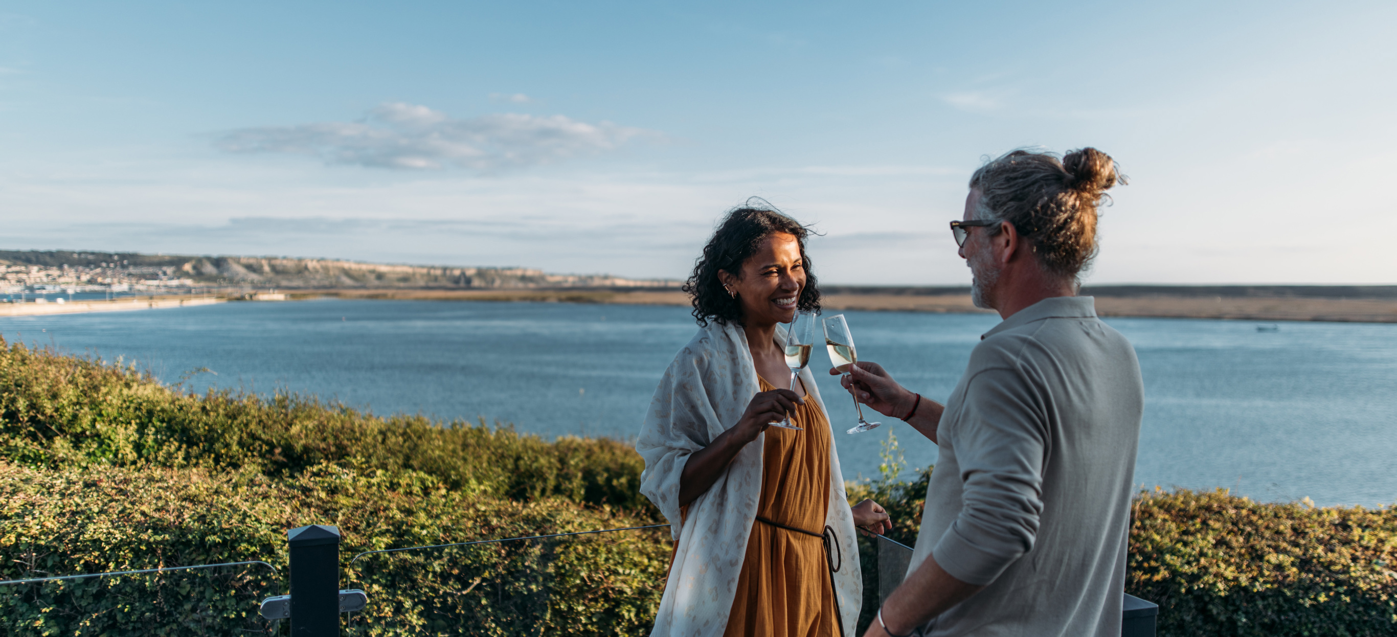 Couple celebrating on deck of holiday home overlooking chesil beach