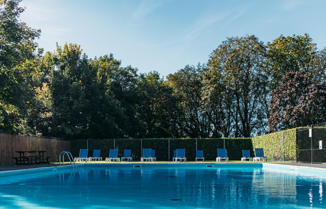 An outdoor pool with a sun terrace and sun loungers on a sunny day