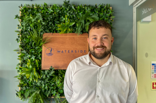 A smiling man stood beside a Waterside sign