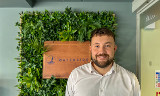 A smiling man stood beside a Waterside sign