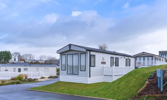 External of a caravan on pitch with decking space and surrounding grass area