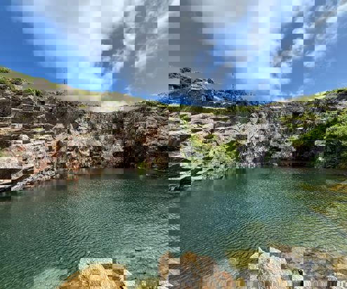 A quarry with a body of water in the centre 