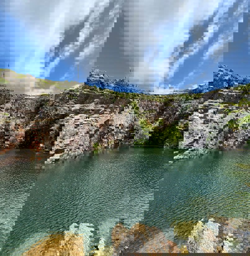 A quarry with a body of water in the centre 