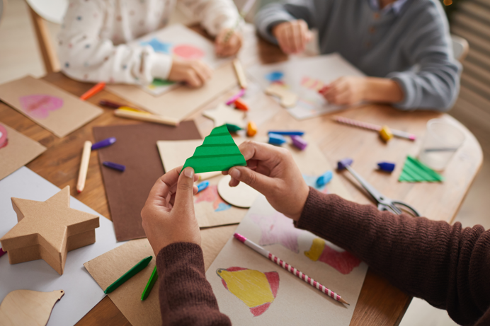 A table full of arts and crafts supplies with children sat around the table