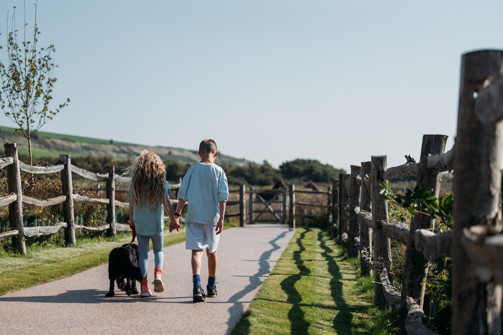 Children walking their dog through countryside on-park