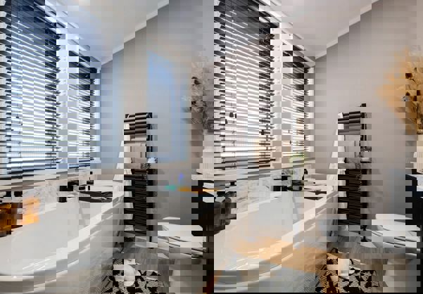 Modern bathroom with bath tub, marble splashbacks and black accessories