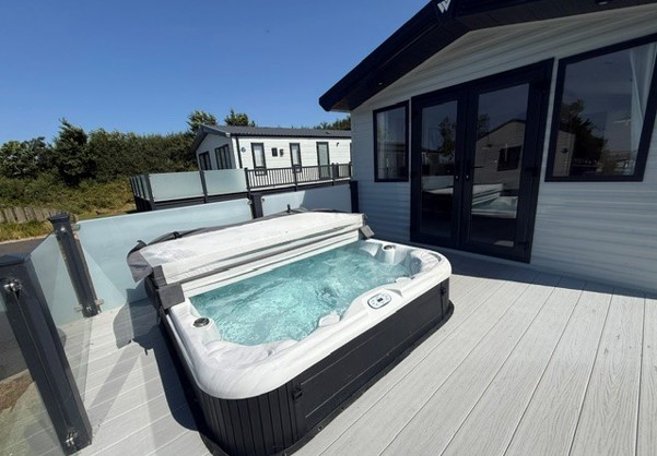 External of a caravan on pitch with decking and hot tub