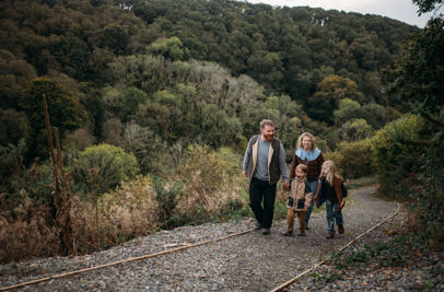 A family of four walking along a nature path among woodland 