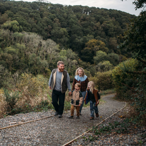 A family of four walking along a nature path among woodland 