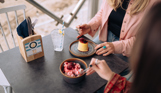 Two women sat at a table in the outside seating area of a restaurant with desserts and beach views