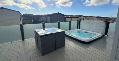 External of a caravan on pitch with decking, hot tub and outdoor furniture