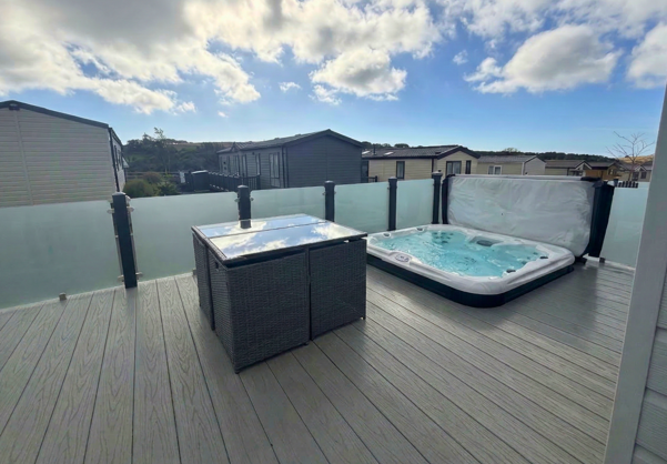 External of a caravan on pitch with decking, hot tub and outdoor furniture
