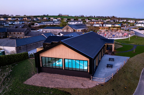 Aerial view of an indoor heated swimming pool within a barn style building with boho-chic styling and countryside views