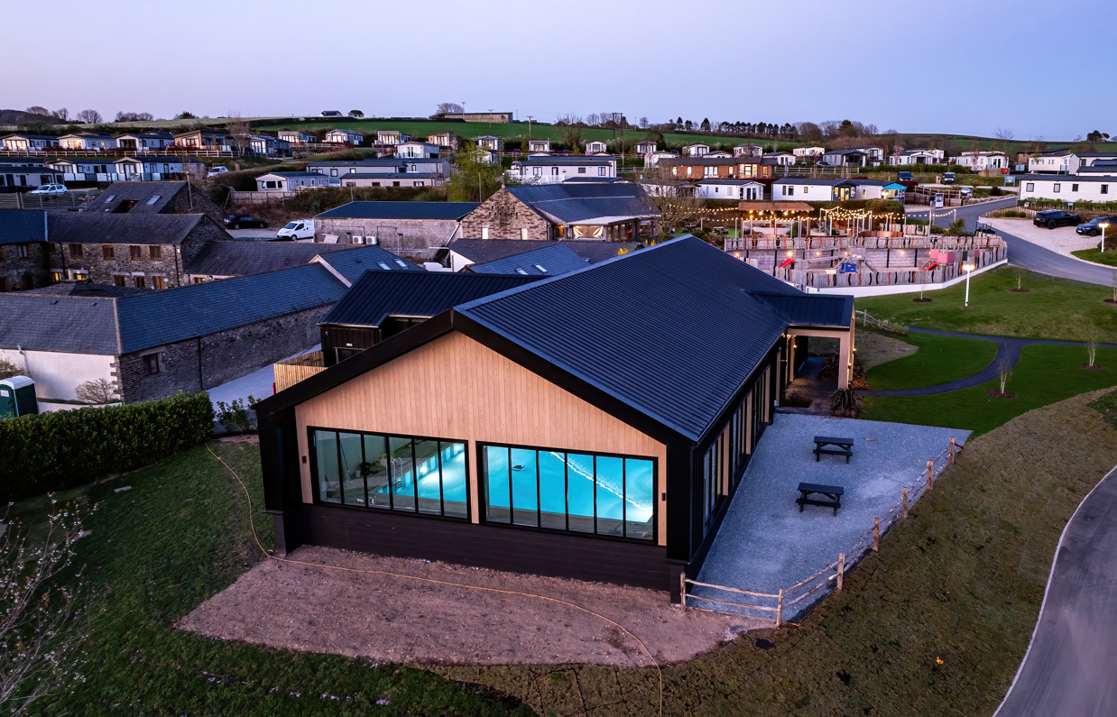 Aerial view of an indoor heated swimming pool within a barn style building with boho-chic styling and countryside views
