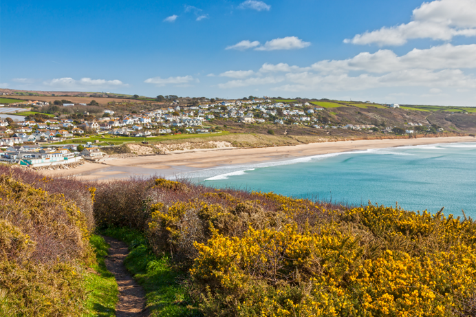 A beach at the bottom of a hill with various houses and buildings nearby 