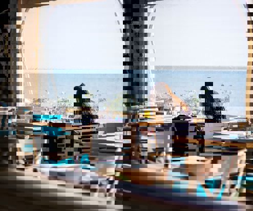 A woman sat at a table in a restaurant with sea views