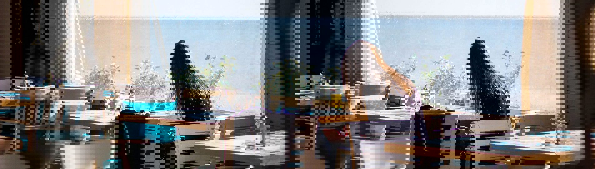 A woman sat at a table in a restaurant with sea views