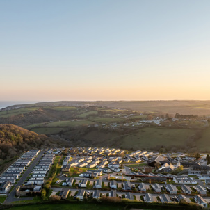 An aerial shot of Tregoad Holiday Park at sunset with views out to sea and Looe Island