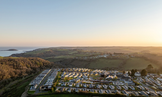 An aerial shot of Tregoad Holiday Park at sunset with views out to sea and Looe Island