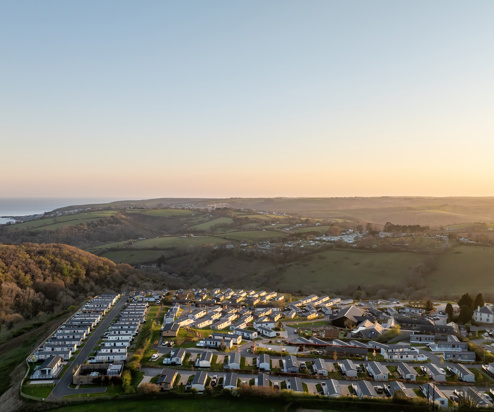 An aerial shot of Tregoad Holiday Park at sunset with views out to sea and Looe Island