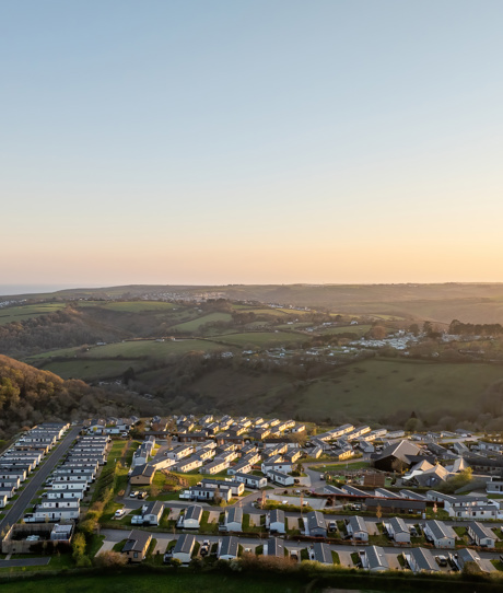 An aerial shot of Tregoad Holiday Park at sunset with views out to sea and Looe Island
