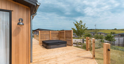 External of a luxury lodge on pitch with decking and hot tub