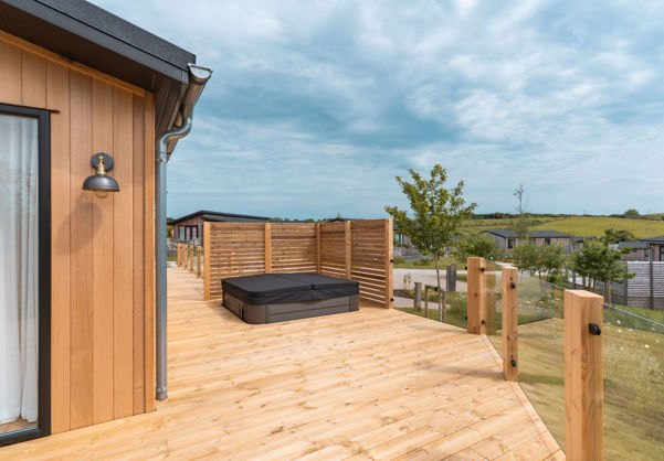 External of a luxury lodge on pitch with decking and hot tub