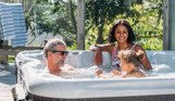 A couple with a young girl in a hot tub at a countryside lodge
