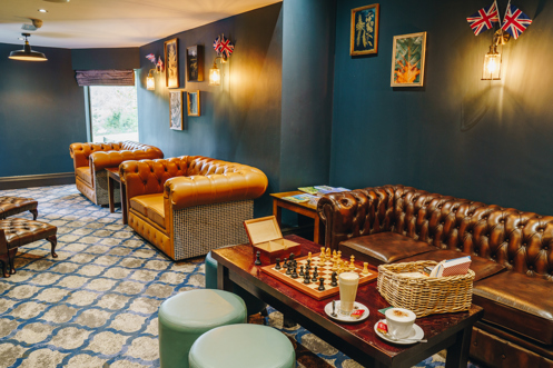 A snug style, moody decor games room with sofas, tables, chess, other games and books as well as coffees