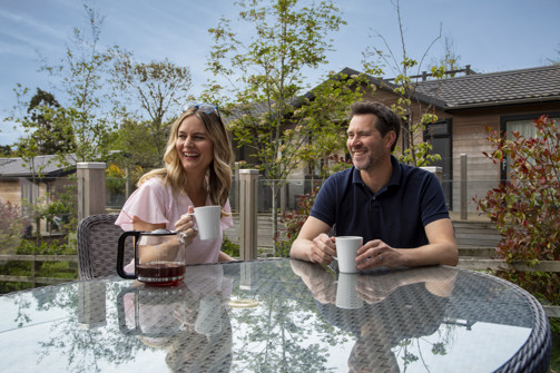 Couple enjoying a cup of tea on the deck of their holiday lodge 