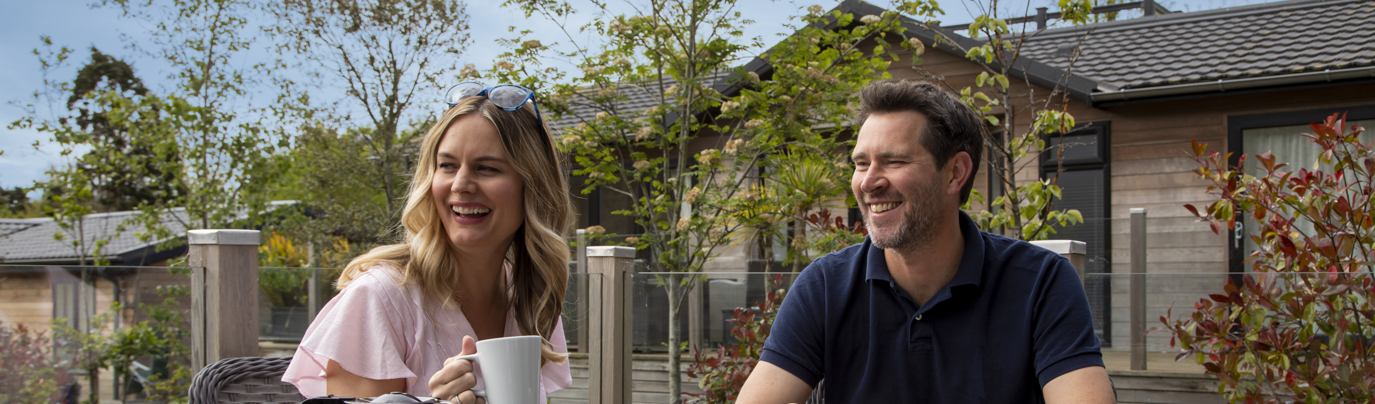 Couple enjoying a cup of tea on the deck of their holiday lodge 