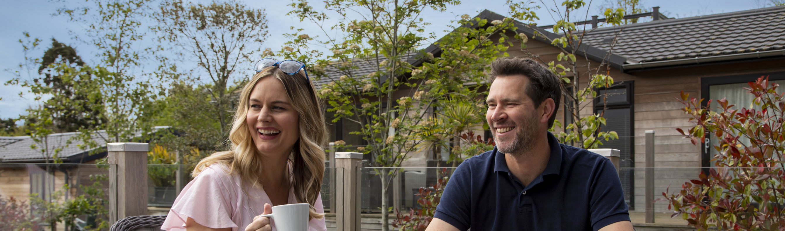 Couple enjoying a cup of tea on the deck of their holiday lodge 