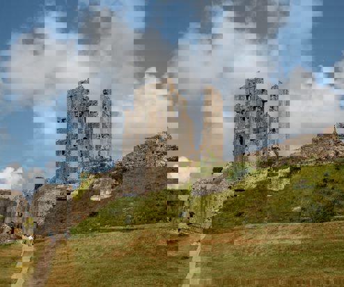 A castle ruins atop a hill with large grassy grounds