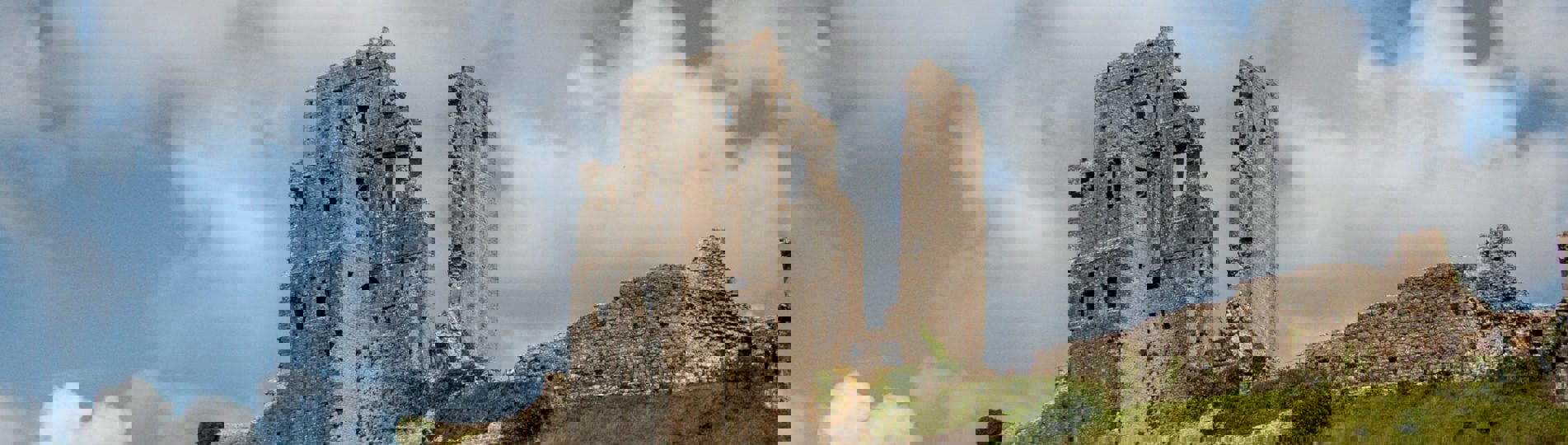 A castle ruins atop a hill with large grassy grounds