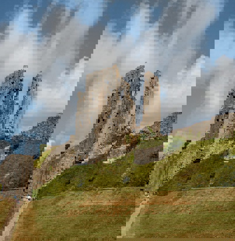 A castle ruins atop a hill with large grassy grounds