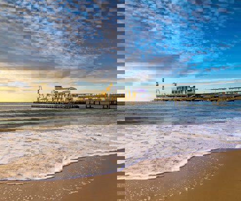 A sandy beach at sunset with a large pier