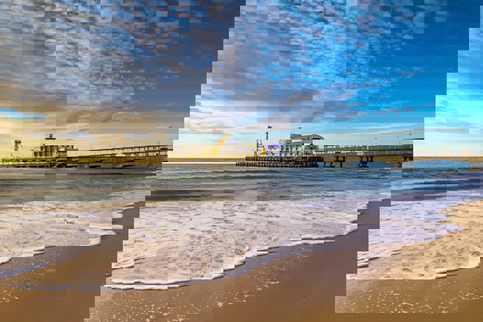 A sandy beach at sunset with a large pier
