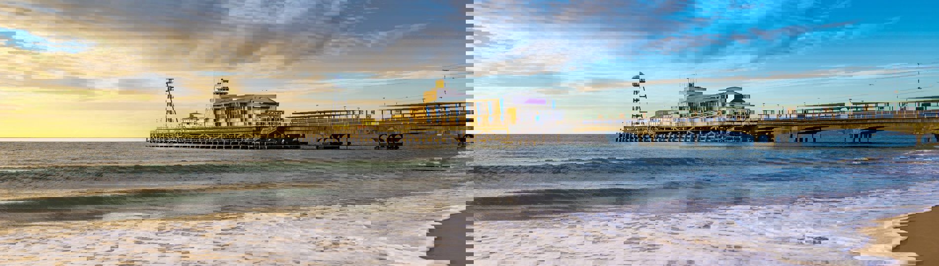 A sandy beach at sunset with a large pier