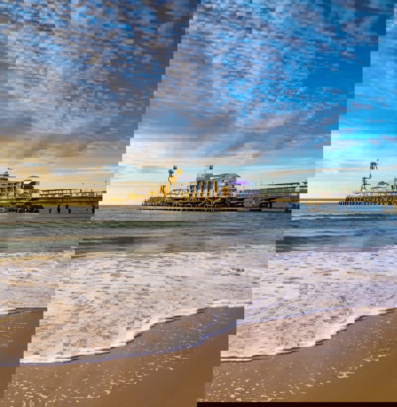 A sandy beach at sunset with a large pier