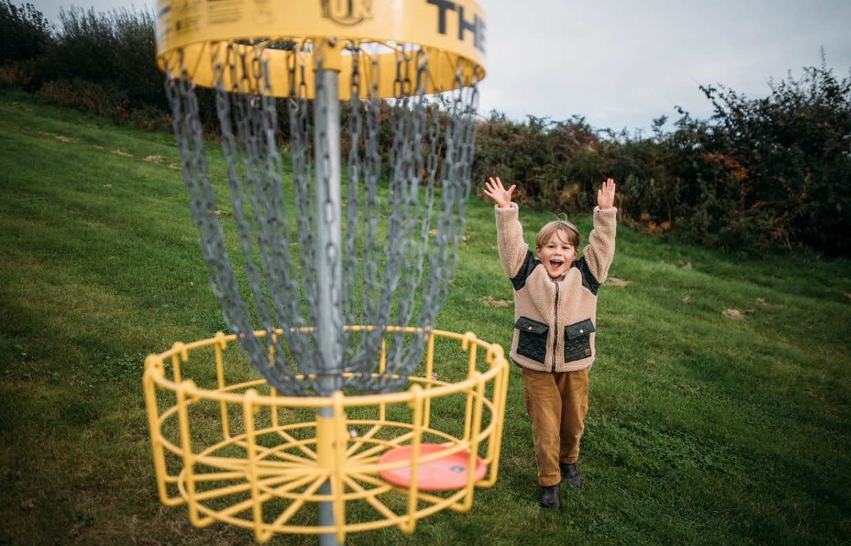 Young boy cheering having scored a goal in frisbee golf