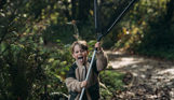 A young boy holding a fishing net up vertically with his tongue out