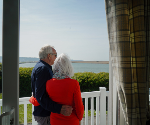 Chesil Beach Owners cuddling on deck looking over lagoon