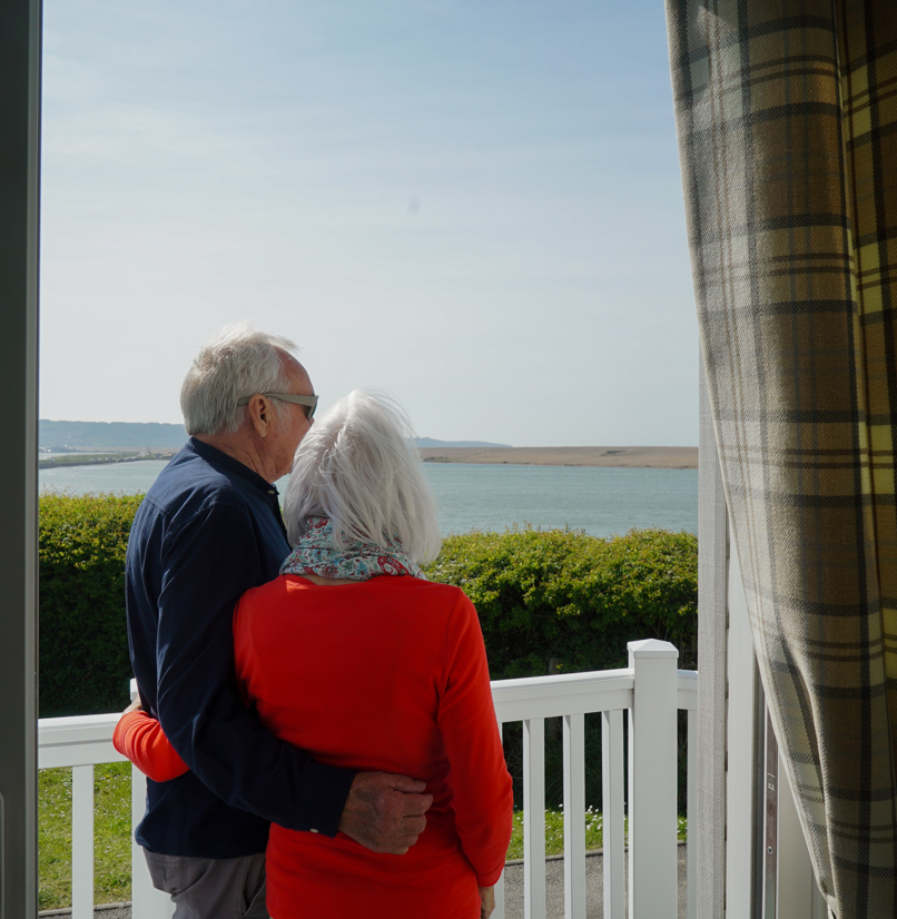 Chesil Beach Owners cuddling on deck looking over lagoon