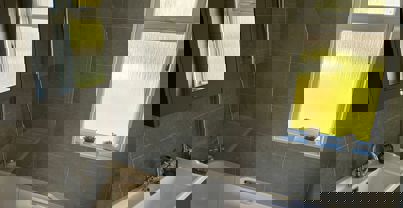 Sleek modern bathroom with tub and integrated shower, and dark grey tiles throughout